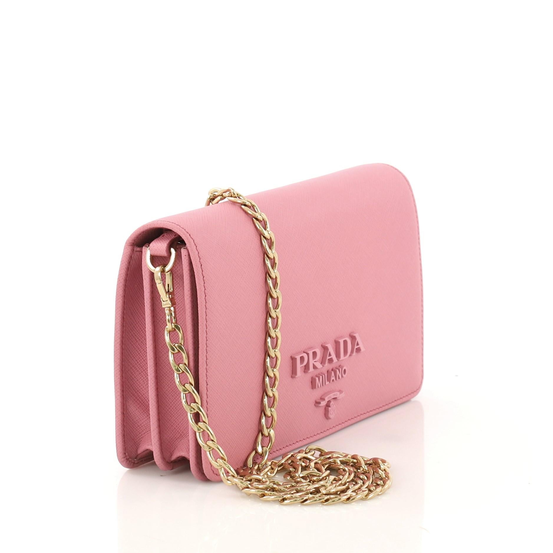 This Prada Chain Flap Bag Saffiano Leather Small, crafted in pink saffiano leather, features chain link shoulder strap, front flap with metal Prada logo and gold-tone hardware. Its magnetic snap closure opens to a red leather interior with a middle