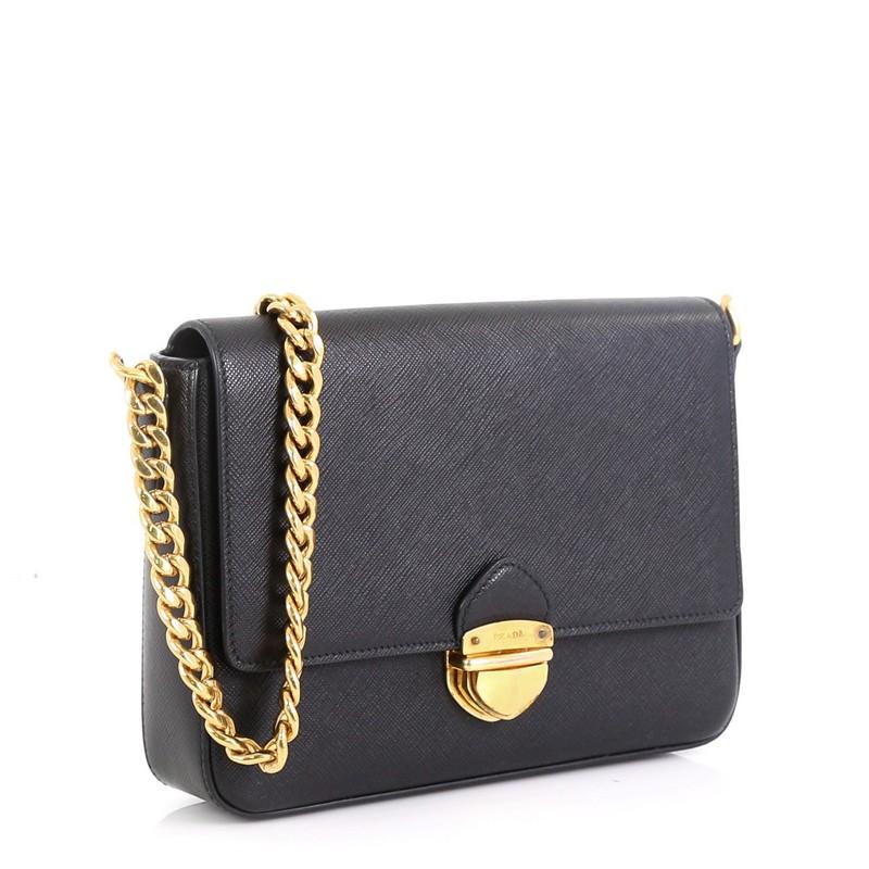 This Prada Chain Flap Bag Saffiano Leather Small, crafted in black saffiano leather, features chain link shoulder strap, front flap with metal Prada logo and gold-tone hardware. It opens to a black fabric interior with zip pocket.

Estimated Retail