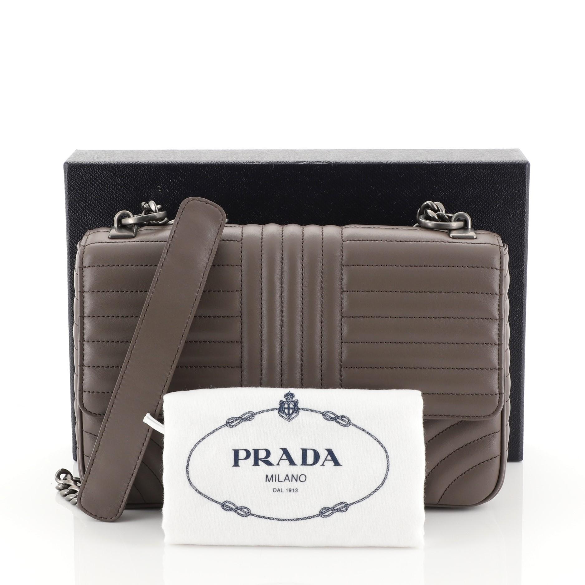 This Prada Chain Flap Shoulder Bag Diagramme Quilted Leather Medium, crafted in neutral diagramme quilted leather, features a sliding chain and leather shoulder strap, flap top with logo lettering and aged silver-tone hardware. Its snap closure