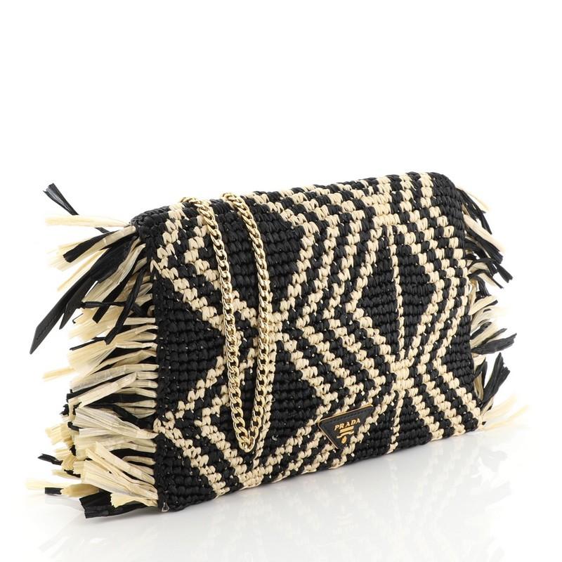 This Prada Chain Flap Shoulder Bag Woven Raffia Small, crafted in black and neutral raffia, features chain-link strap and fringe trims  Its snap closure opens to a black fabric interior. 

Condition: Very good. Moderate loss of shape on side