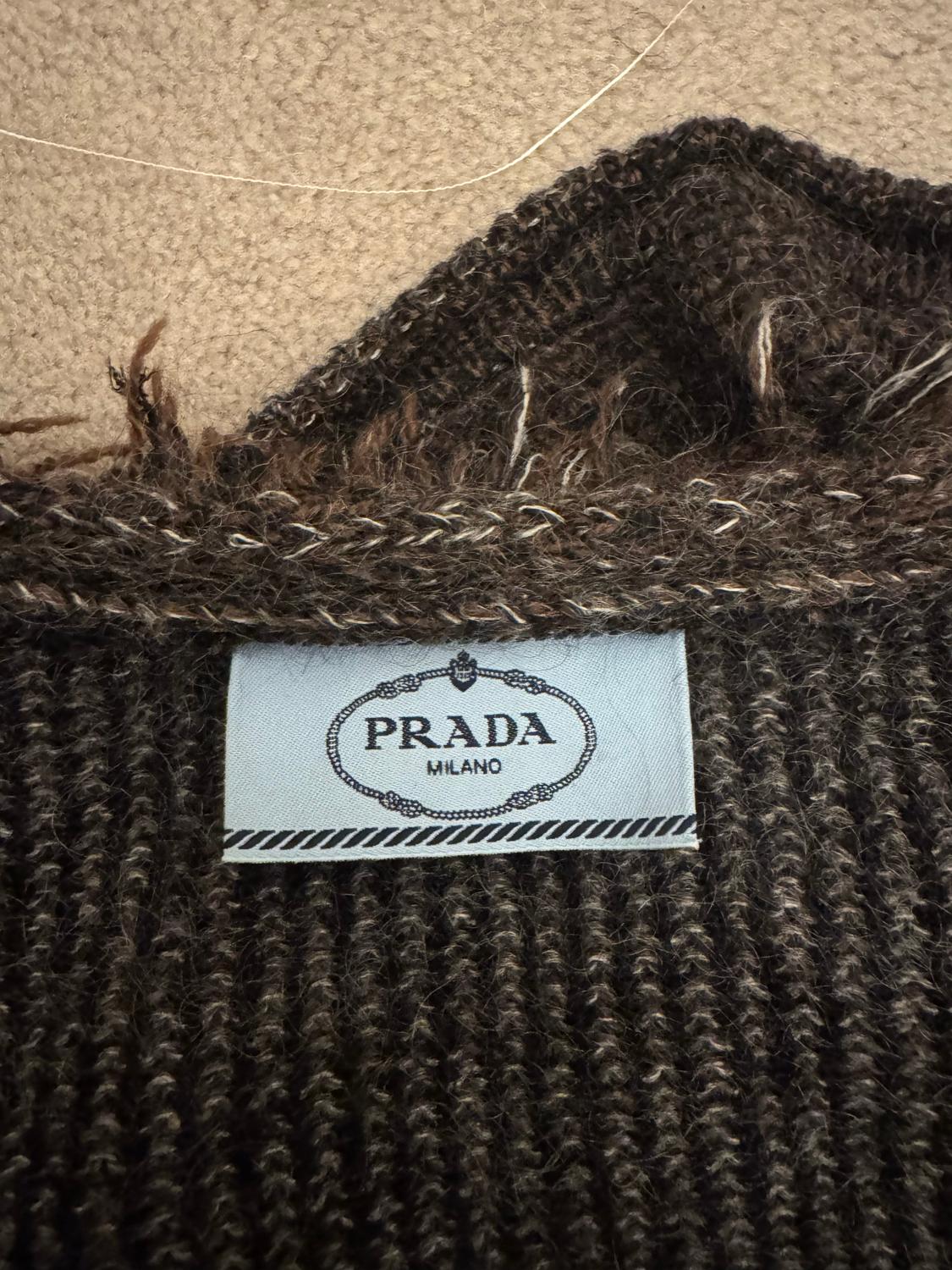 A chic and cosy , cardigan /.jacket by Prada. In an attractive , black, brown and white mix , cardigan has a round nekcline with frill detail. It fastens with poppers and two small pockets on the front.  Made of a wool and mohair mix.  Made in