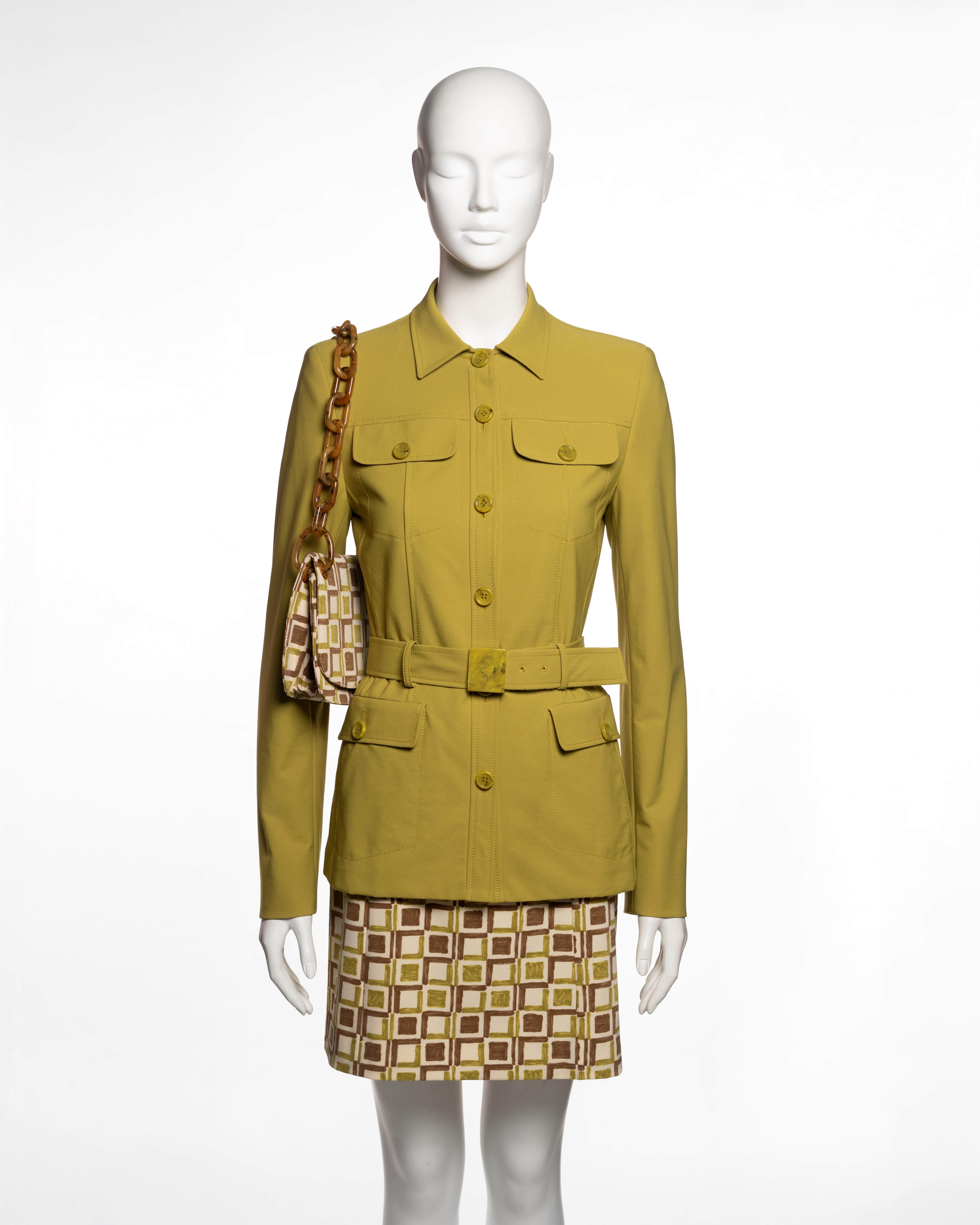 Cet ensemble pour femme de la collection Printemps-Été 1996 de Prada comprend une veste de style safari en gabardine de nylon mélangé chartreuse, une mini-jupe ajustée et un sac à bandoulière assorti. La veste présente une taille ceinturée avec une