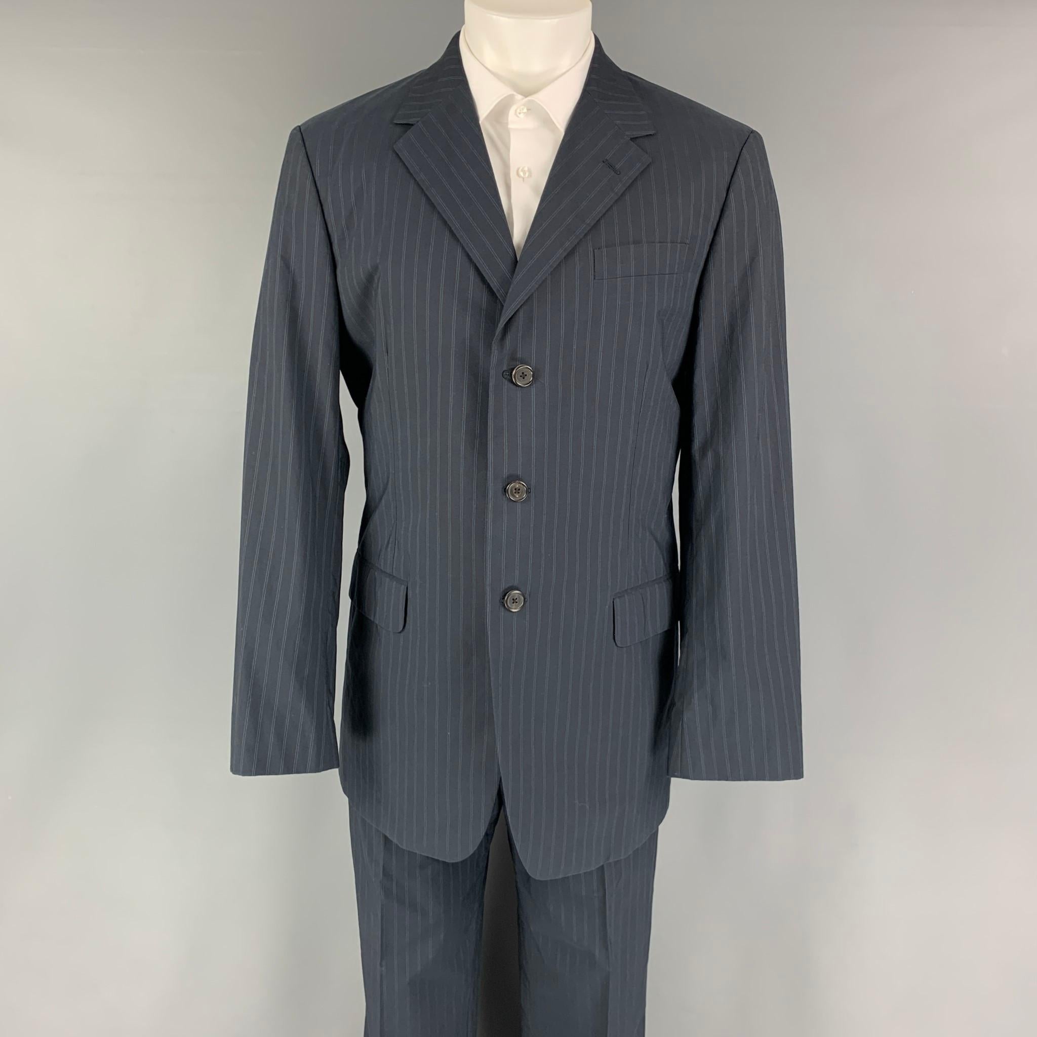 PRADA suit comes in a navy stripped cotton woven material with a full liner and includes a single breasted, three button sport coat with a notch lapel and matching flat front trousers. Made in Italy.

Excellent Pre-Owned Condition.
Marked:
