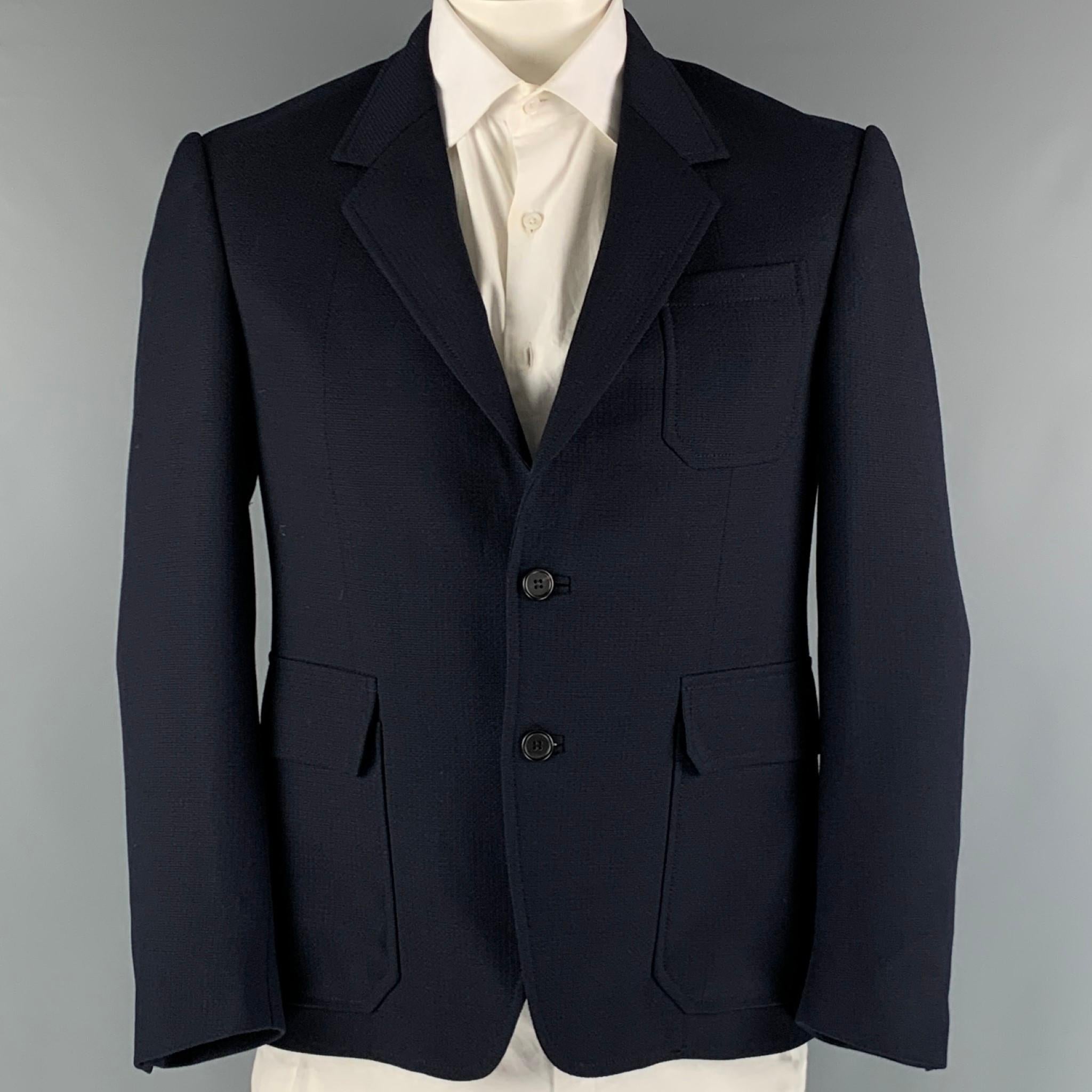 PRADA sport coat comes in a navy wool and mohair woven material with no lining featuring a notch lapel, patch pockets, single back vent, and a double button closure.

Excellent Pre-Owned Condition.
Marked: 52 S

Measurements:

Shoulder: 18