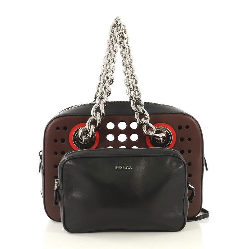 This Prada City Fori Chain Shoulder Bag Perforated Calfskin Small, crafted in burgundy and black perforated calfskin leather, features dual chunky chain-link handles and silver-tone hardware accents. Its zip closure opens to a black leather-lined