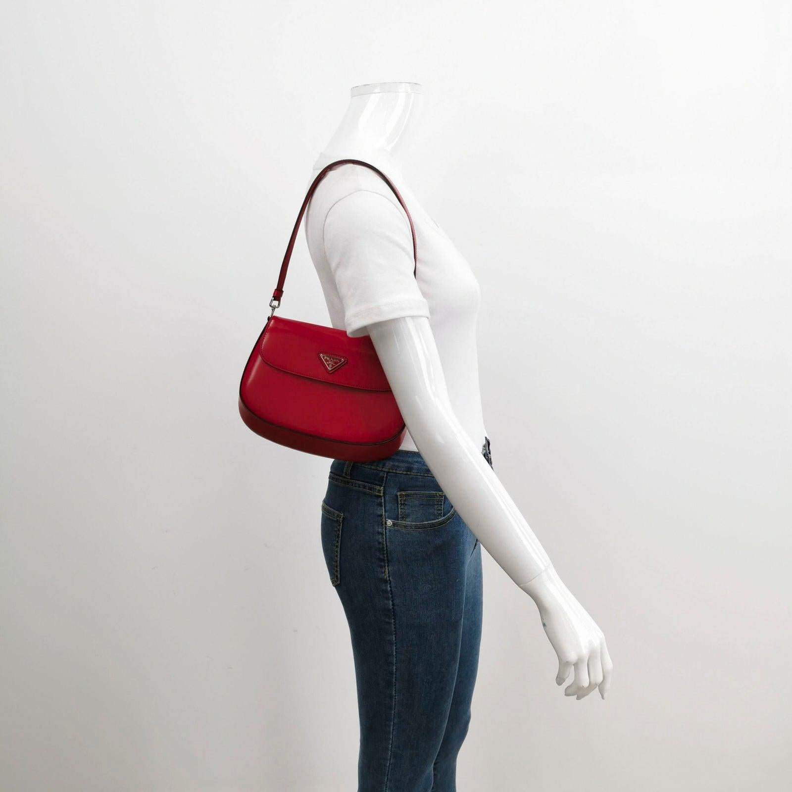 Prada Cleo Flap Red Leather Small Shoulder bag
  These are professional photos of the actual bag.
  This Prada Cleo Flap Shoulder Bag is the perfect accompaniment for any stylish and sophisticated woman. Crafted from smooth burgundy/red leather and