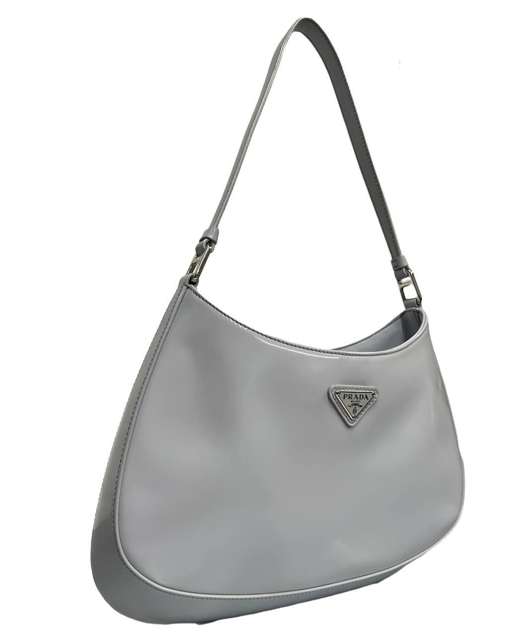 Shoulder bag by Prada model Cleo, representing an iconic design reinterpreted by the brand of the 90s, in Cornflower-colored brushed leather with silver hardware.

It has a button closure. The interior is lined with a soft black fabric and is