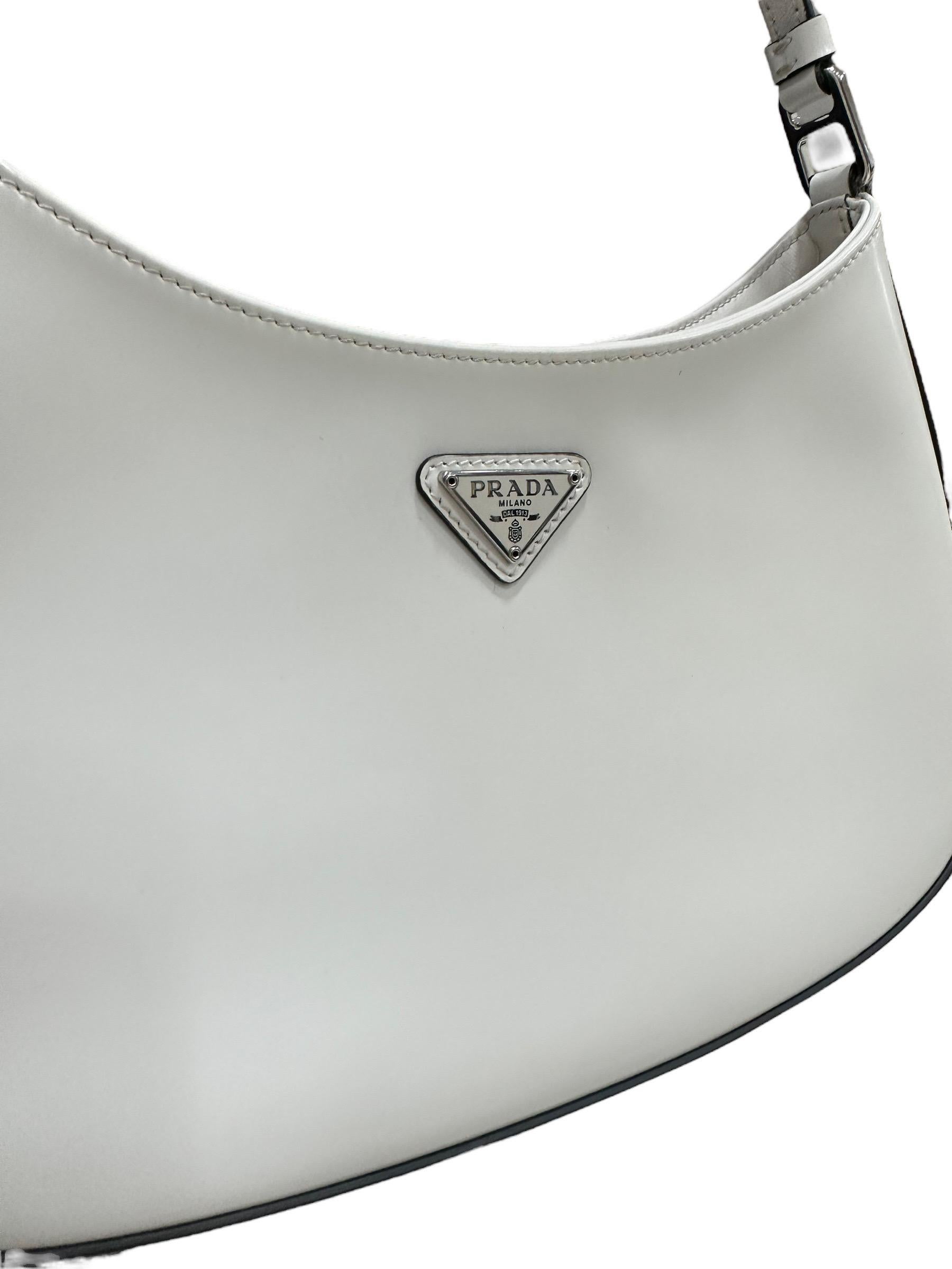 Prada shoulder bag, Cleo model, made of white brushed leather, with black leather trim and silver hardware. Equipped with an internal magnetic button closure, covered in black fabric, roomy for the essentials. Fitted with a non-adjustable top handle