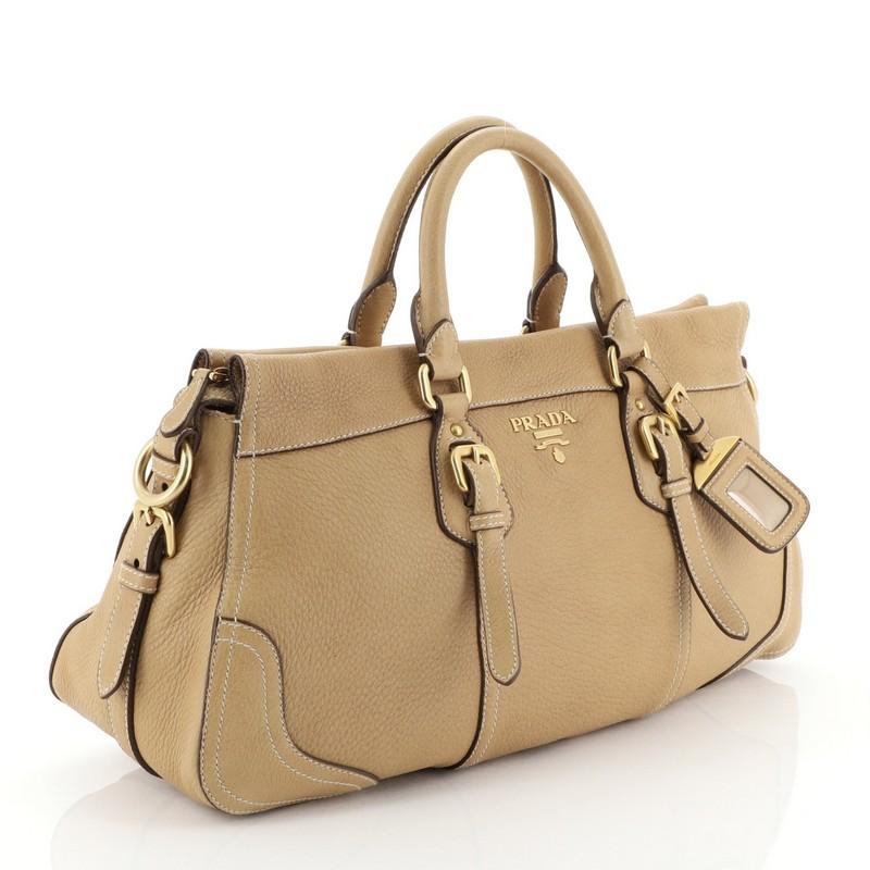 This Prada Convertible Belted Satchel Vitello Daino Large, crafted in neutral vitello daino leather, features dual rolled handles, belted accents, and gold-tone hardware. Its zip closure opens to neutral fabric interior with side zip and slip