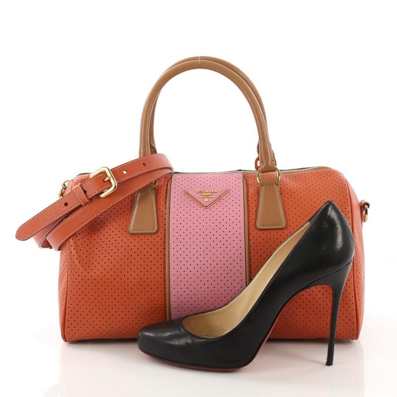 This Prada Convertible Boston Bag Perforated Leather Medium, crafted from orange/pink peforated leather, features dual rolled leather handles, raised Prada logo and gold-tone hardware. Its zip closure opens to a gold fabric interior with zip and
