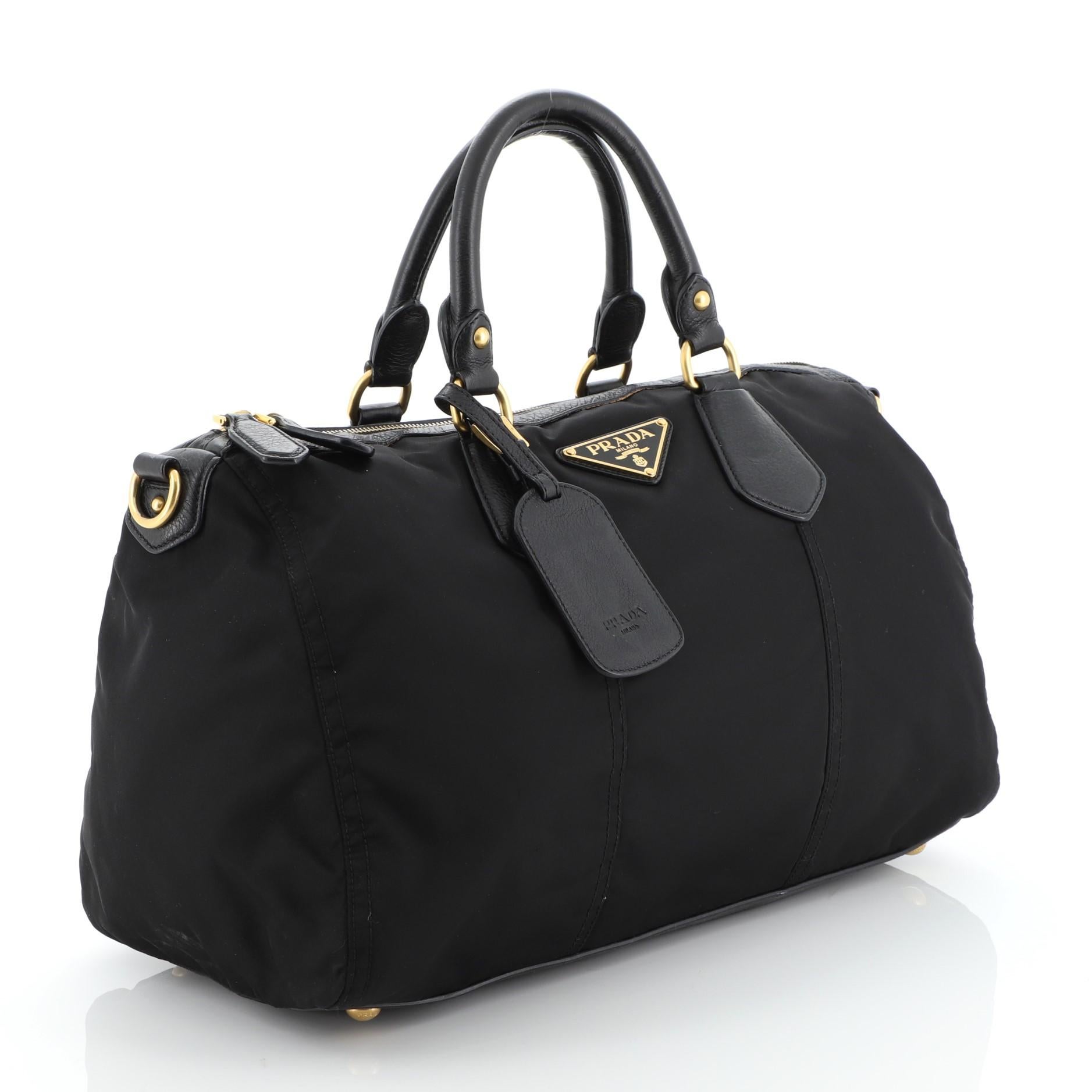 This Prada Convertible Boston Bag Tessuto Large, crafted from black tessuto, features dual rolled leather handles, signature Prada logo and gold-tone hardware. Its zip closure opens to a black fabric interior. 

Condition: Very good. Odor in
