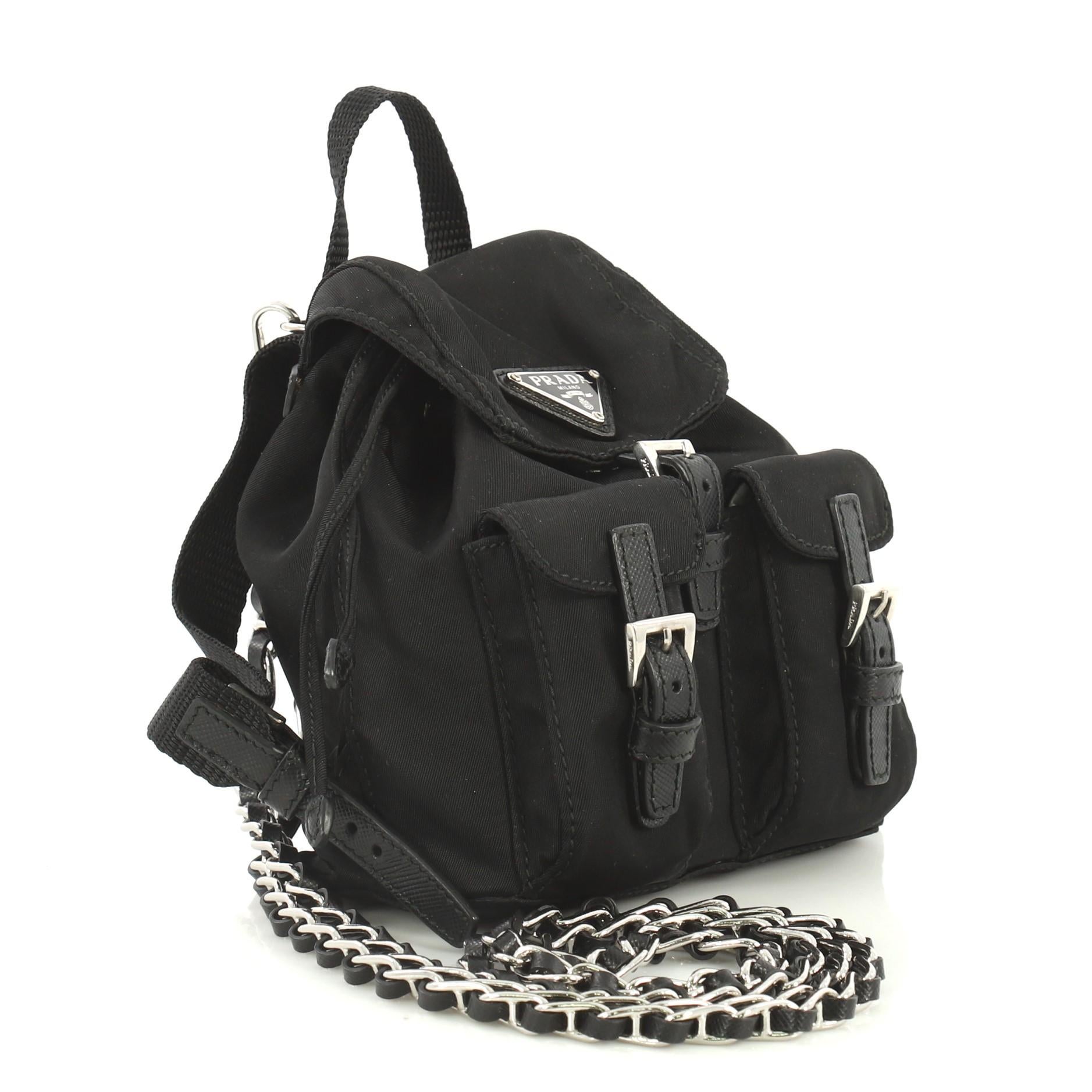 This Prada Convertible Chain Backpack Tessuto Mini, crafted from black tessuto fabric, features top handle, adjustable backpack straps, removable chain crossbody strap, two exterior front flap pockets and silver-tone hardware. Its flap with snap