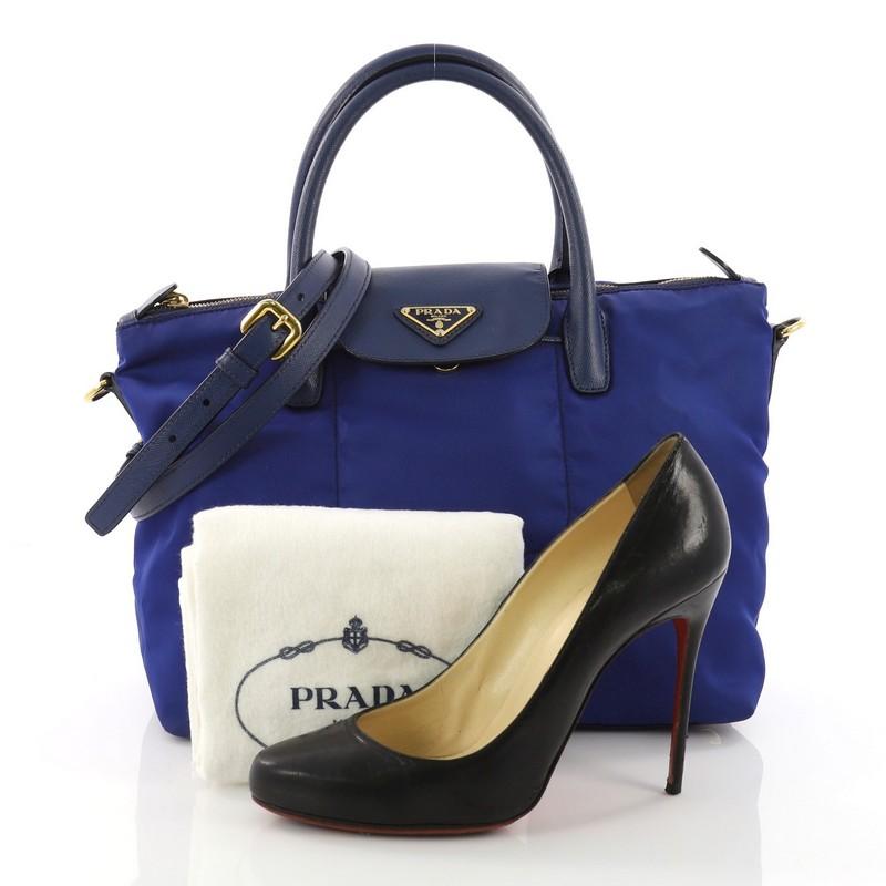 This Prada Convertible Flap Tote Tessuto and Saffiano Leather Medium, blue tessuto and saffiano leather, features dual rolled leather handles, detachable adjustable shoulder strap, and gold-tone hardware. Its zip closure opens to a blue fabric
