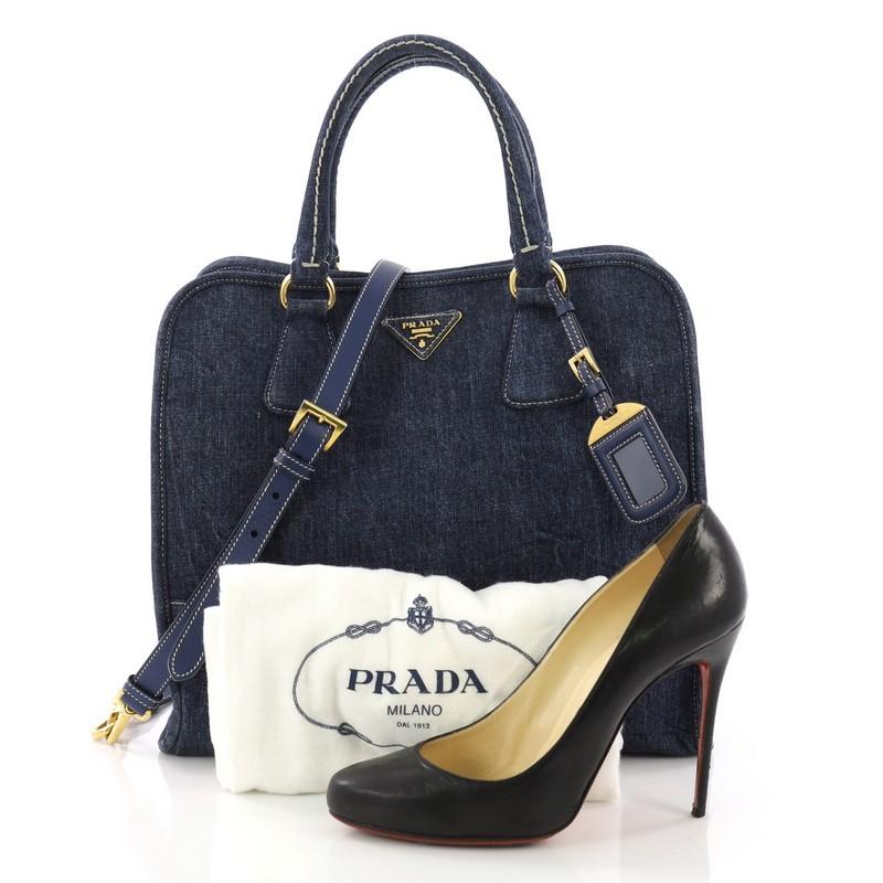 This Prada Convertible Open Tote Denim Medium, crafted in blue denim, features a raised Prada logo at the center, dual rolled leather handles, and gold-tone hardware. Its snap button closure opens to an orange and white fabric interior with side zip