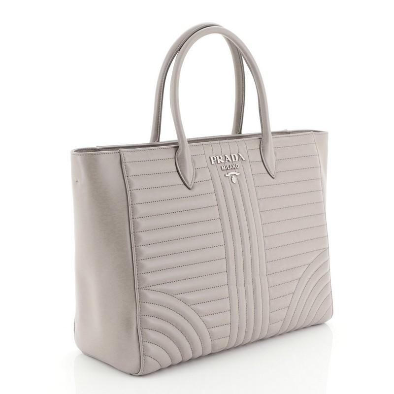 This Prada Convertible Open Tote Diagramme Quilted Leather Medium, crafted from neutral diagramme quilted leather, features dual top handles and silver-tone hardware. It opens to a gray fabric interior. 

Estimated Retail Price: $1,990
Condition: