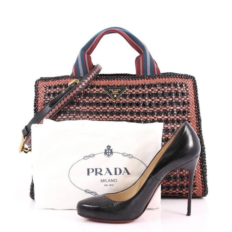 This authentic Prada Convertible Open Tote Madras Woven Leather Medium is a stylish and functional bag perfect for your daily excursions. Crafted in black and mauve woven leather, this tote features dual nylon handles, Prada triangle logo,