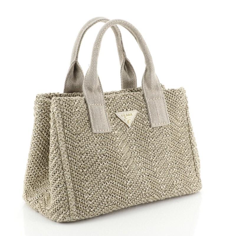 This Prada Convertible Open Tote Woven Raffia Mini, crafted in neutral woven raffia, features dual top handles and gold-tone hardware. It opens to a neutral canvas interior. 

Condition: Damaged. Missing code. Wear and fraying on exterior, handles,