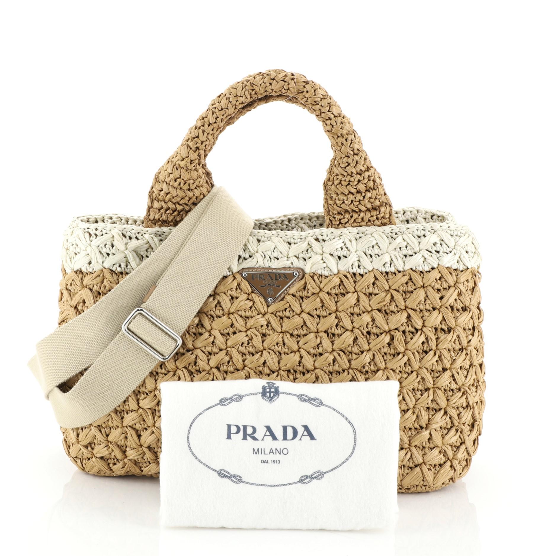 This Prada Convertible Open Tote Woven Raffia Small, crafted from neutral woven raffia, features dual top handles, inverted Prada triangle logo at the center, and silver-tone hardware. It opens to a neutral fabric interior. 

Condition: Great. Minor