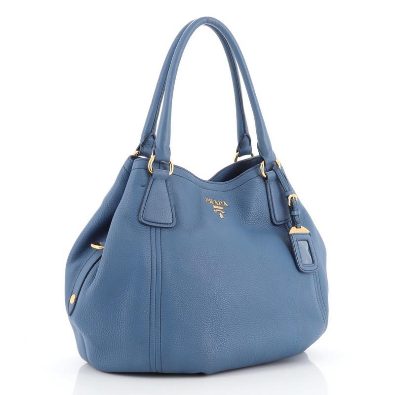 This Prada Convertible Satchel Vitello Daino Medium, crafted from blue vitello daino leather, features dual rolled leather handles, Prada Milano logo, and gold-tone hardware. It opens to a blue fabric interior with side zip pocket. 
Estimated Retail