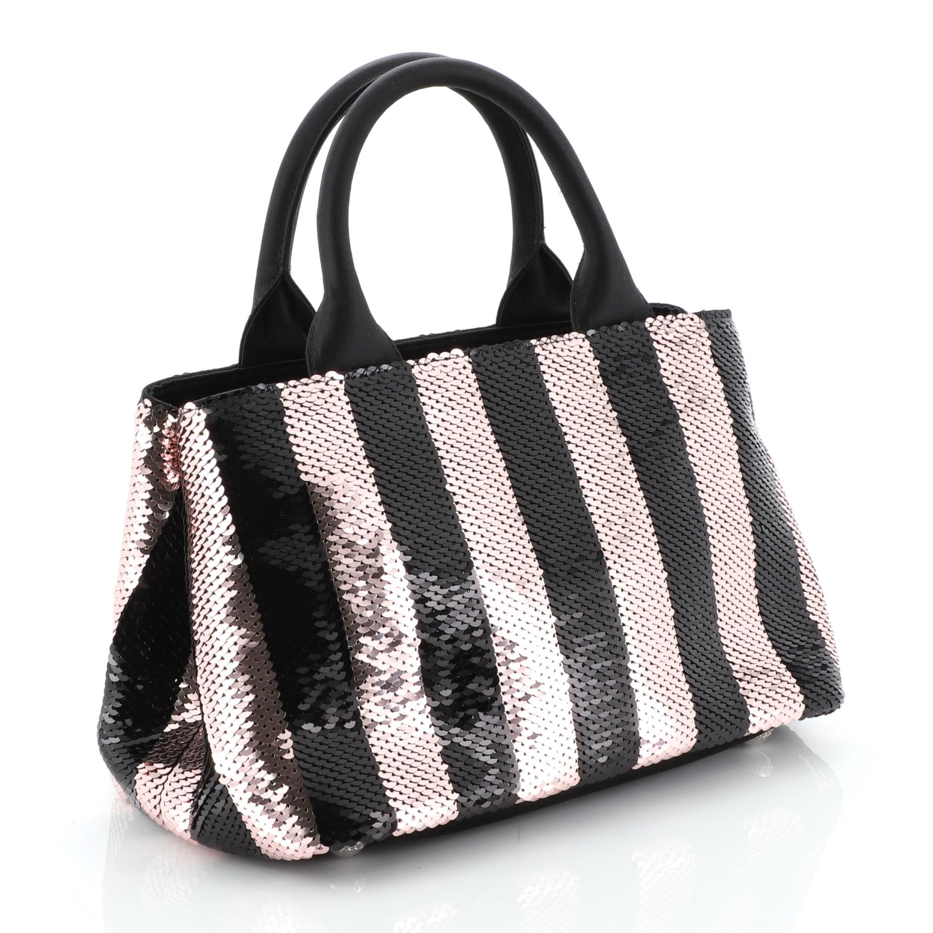 This Prada Convertible Tote Sequin Embellished Satin Small, crafted from black and pink sequin embellished satin, features dual rolled handles and silver-tone hardware. Its zip closure opens to a black satin interior with side zip and slip pockets.
