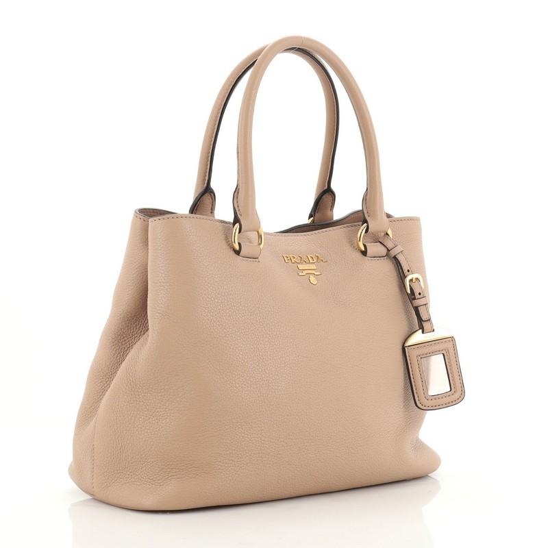 This Prada Convertible Tote Vitello Phenix Medium, crafted in neutral vitello phenix leather, features dual rolled leather handles, Prada logo at the center and gold-tone hardware. It opens to a neutral fabric interior with a middle zip compartment