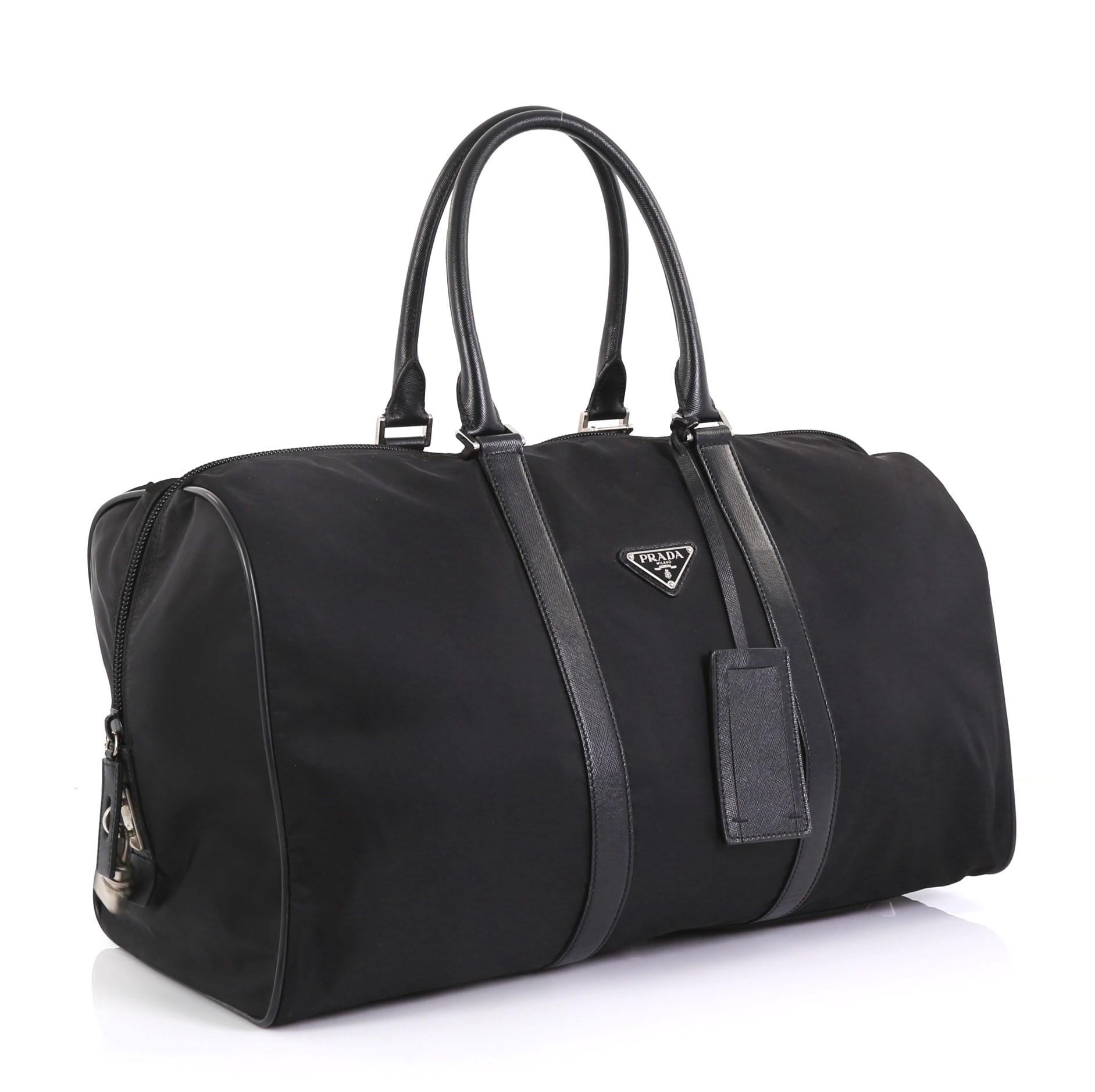 This Prada Convertible Weekender Bag Tessuto with Saffiano Leather Large, crafted with black tessuto, features dual rolled handles, leather trim, inverted triangle Prada logo, and silver-tone hardware. Its top zip closure opens to a black fabric