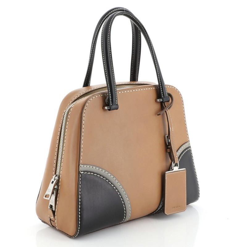This Prada Convertible Zip Around Satchel Vachetta Leather Medium, crafted from brown and multicolor vachetta leather, features dual top handles and silver-tone hardware. Its zip-around closure opens to a brown leather interior with slip and flap