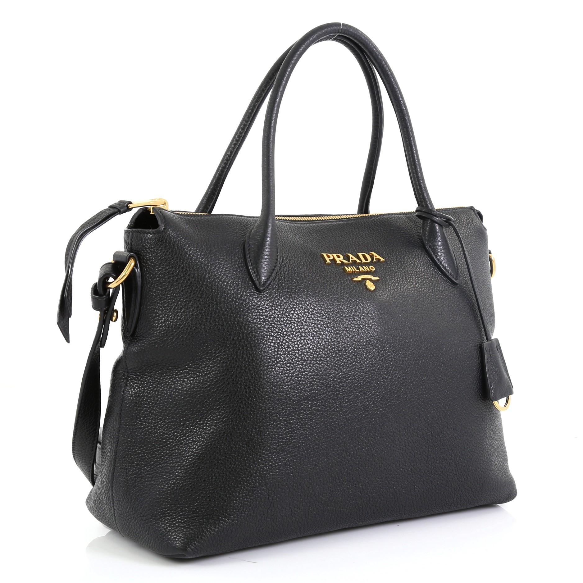 This Prada Convertible Zip Satchel Vitello Daino Medium, crafted in black leather, features dual-rolled leather handles, detachable strap, Prada logo at the center, and gold-tone hardware. Its zip closure opens to a black fabric interior with zip