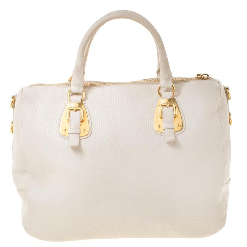 This bowler bag from Prada is not only artistic in design but also high on style. Crafted from leather, the cream bag features dual handles with an attached tag accent and protective metal feet. The top zipper opens to a spacious nylon-lined