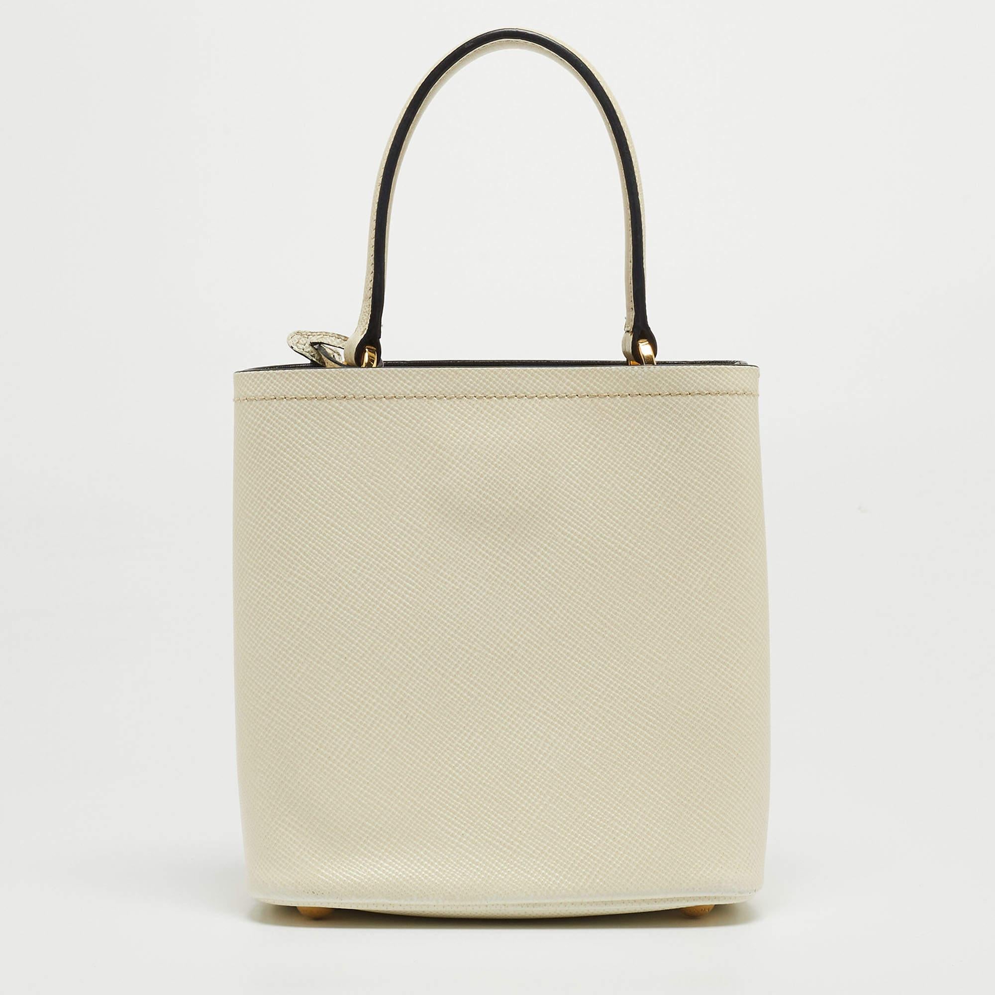 Prada's signature trait of luxury and class is displayed in this bag from the Panier collection. It is a top-handle leather bag that comes with a detachable strap and has the brand's logo fitted on the front in gold-tone metal. This cream-hued bag