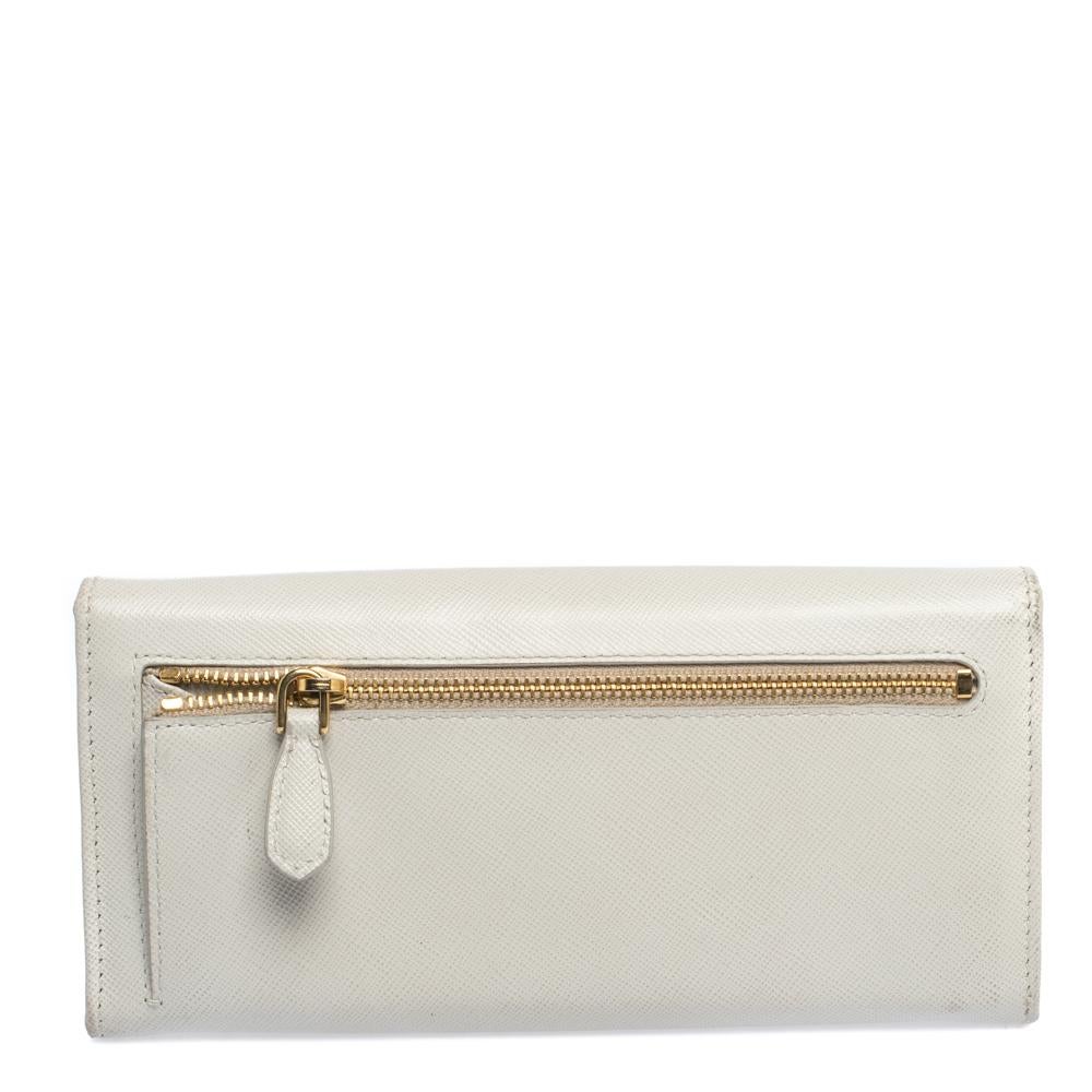 Take this spacious and functional flap wallet by Prada everywhere. Made from cream Saffiano Lux leather, this flap wallet is accented with a gold-tone logo. The easy to organize interior is lined with leather & fabric and features compartments,