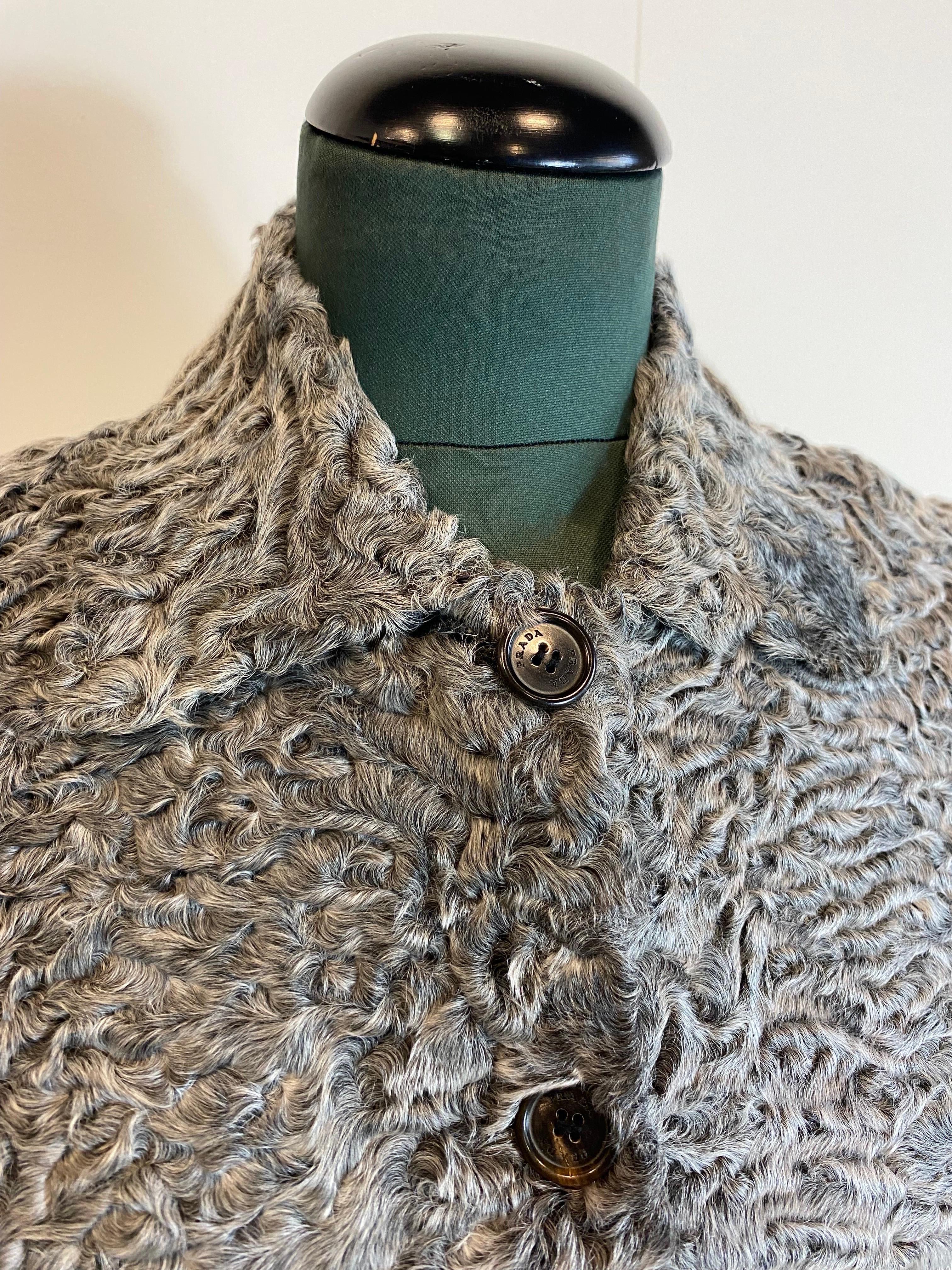 Prada Crop Top Bomberjacke aus grauem Astrakhan-Pelz. 
Mit Logoknöpfen.
Mit Kragen. Innenausstattung aus schwarzem Leder.
Größe 38. 
Schulter 42
Hülse 62
Brustkorb 48
Länge 53
Leben 33
Seitennähte bei genauem Hinsehen sichtbar, Belüftungsöffnungen