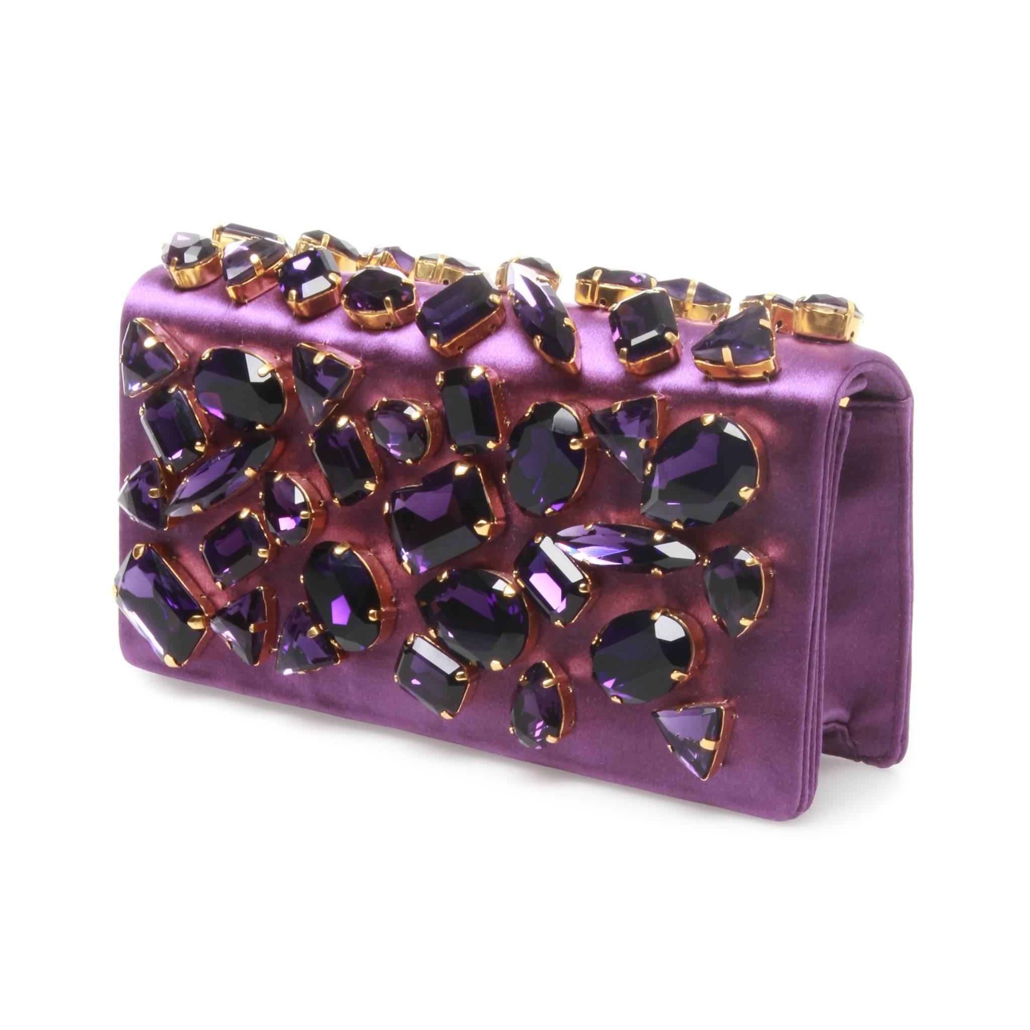 A pristine PRADA Swarovski Crystal embellished Satin Clutch Bag.
It features a beautiful chunky Swarovski crystal in purple on the flap with button closure and open pocket slot inside.
It can be used a clutch or a crossbody bag with detachable