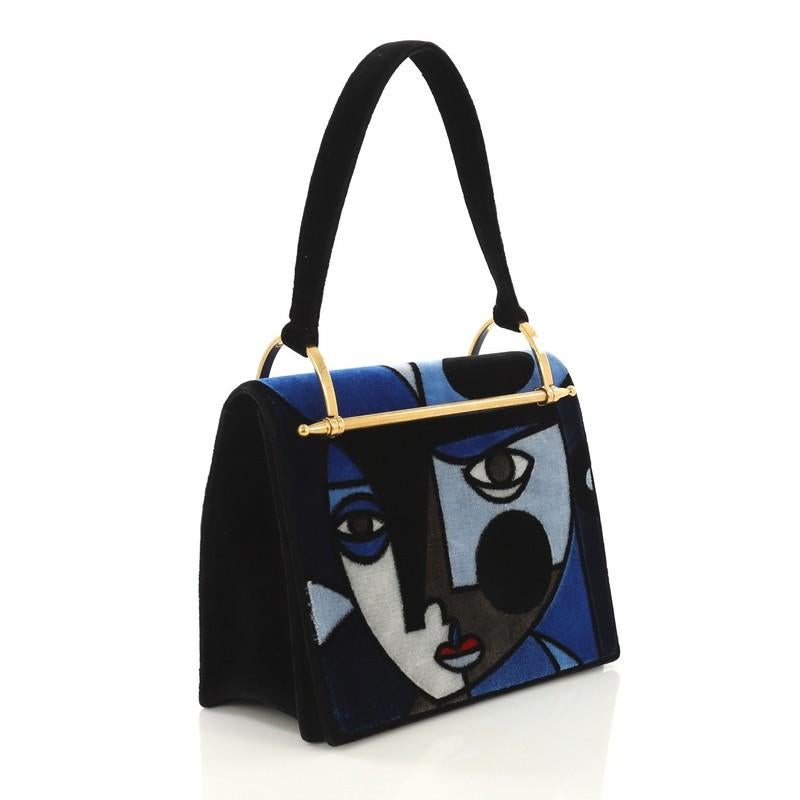 This Prada Cubist Top Handle Bag Printed Velvet, crafted in blue and black printed velvet, features single loop top handle, metal frame, and aged gold-tone hardware. Its magnetic snap closure opens to a black suede and fabric interior with side zip