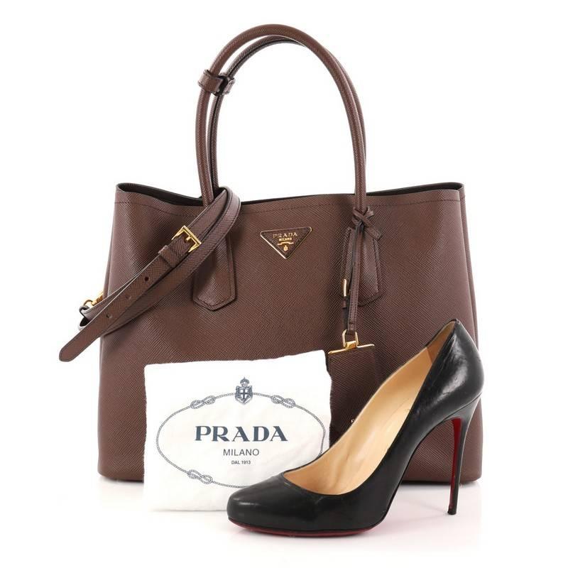 This authentic Prada Cuir Double Tote Saffiano Leather Medium is elegant in its simplicity and structure. Crafted from sturdy cacao brown saffiano leather, this tote features dual-rolled handles, side snap buttons, Prada's trademark triangle logo at