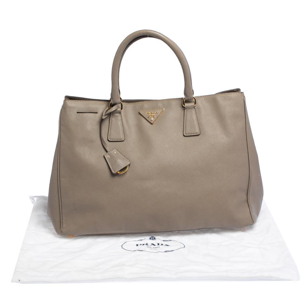 The Gardener's tote by Prada is a wonderful creation. This here is crafted from Saffiano Lux leather and shaped to exude a look of luxury. The bag comes with two handles and a spacious nylon interior for your belongings. Protective metal feet and