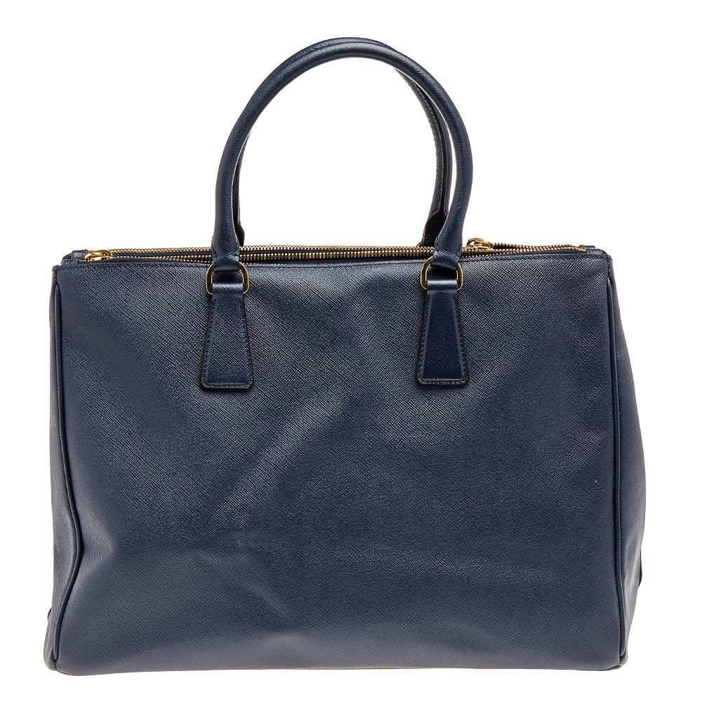 Appreciated globally for its classic and functional silhouette, the Galleria tote from Prada is undoubtedly one of the most significant creations by the brand. It has been made using dark-blue Saffiano Lux leather with a double zip enclosing a