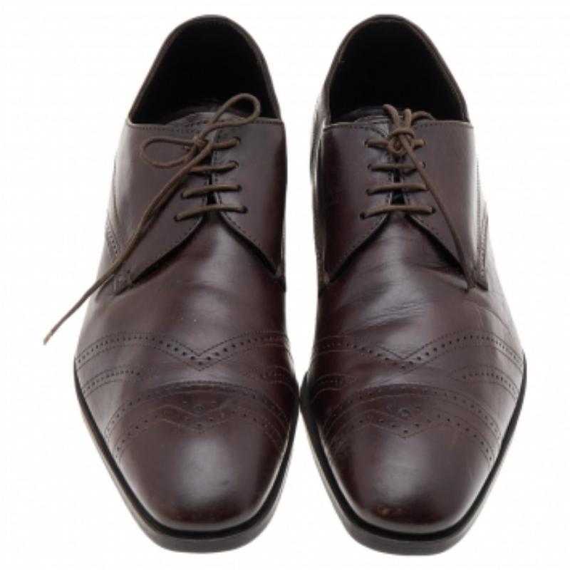 Give your formals a grand touch with these shoes by Prada! Crafted from leather in a dark brown shade, this pair features lace-up closure and brogue detailing on the vamps. The leather insole and small heel complete the look.