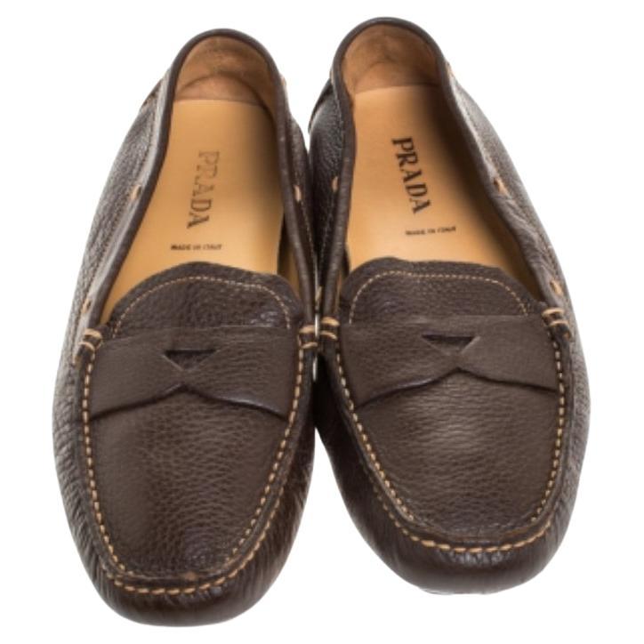 Estos mocasines de Prada son los favoritos de las mujeres que siguen la moda. Están bellamente confeccionadas en piel marrón oscura con detalles de tiras en los empeines. Completados con plantillas forradas de piel, cálzate estos mocasines para un