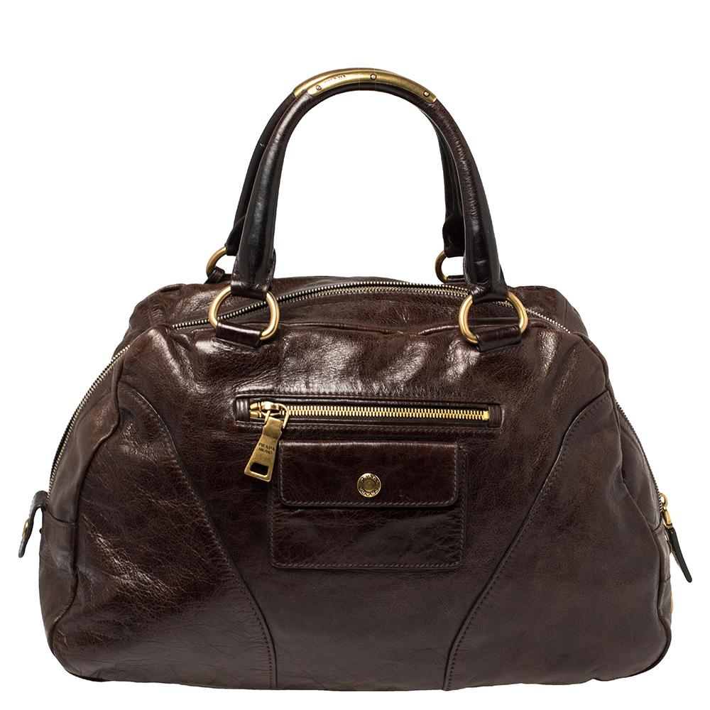 Luxury and elegance are personified with this brilliantly crafted Bowler bag from Prada. The bag is made using Vitello Shine leather and complemented by gold-tone hardware. It has two handles and the zip-top closure opens to a leather-lined interior