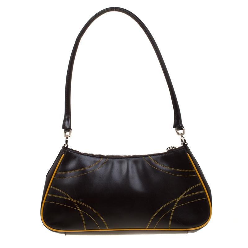 Meant for you to carry all your essentials with ease is this bag by Prada. Crafted from brown and yellow leather, the bag has stitch detailing, a single handle, and a nylon interior to hold your belongings. This bag is pure style with charming