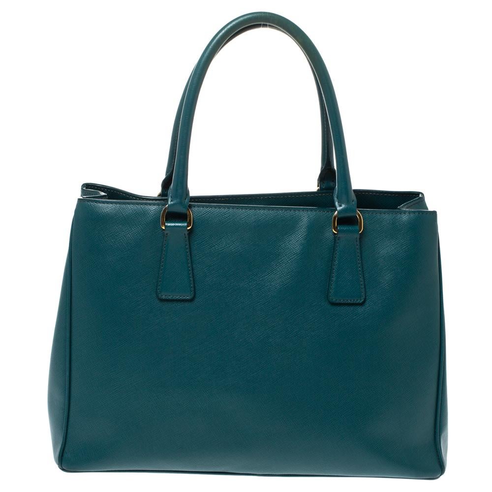 Loved for its classic appeal and funtional design, Galleria is one of the most iconic and popular bags from the house of Prada. This beauty in green is crafted from leather and is equipped with two top handles, the brand logo at the front and a