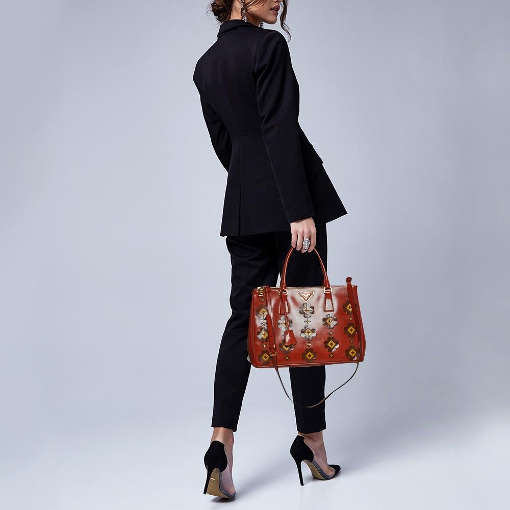 Feminine in shape and grand on design, this Double Zip tote by Prada will be a loved addition to your closet. It has been crafted from leather and styled with floral appliques all over the exterior along with gold-tone hardware. It comes with dual