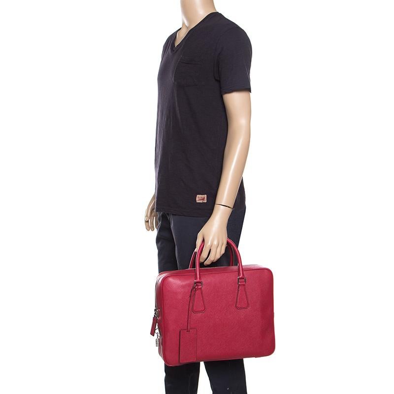 The house of Prada is known for their exquisite yet functional designs and this briefcase embodies just that. Crafted from red Saffiano leather, the bag features a wide silver-tone zipper that opens up to reveal a leather compartment perfectly sized
