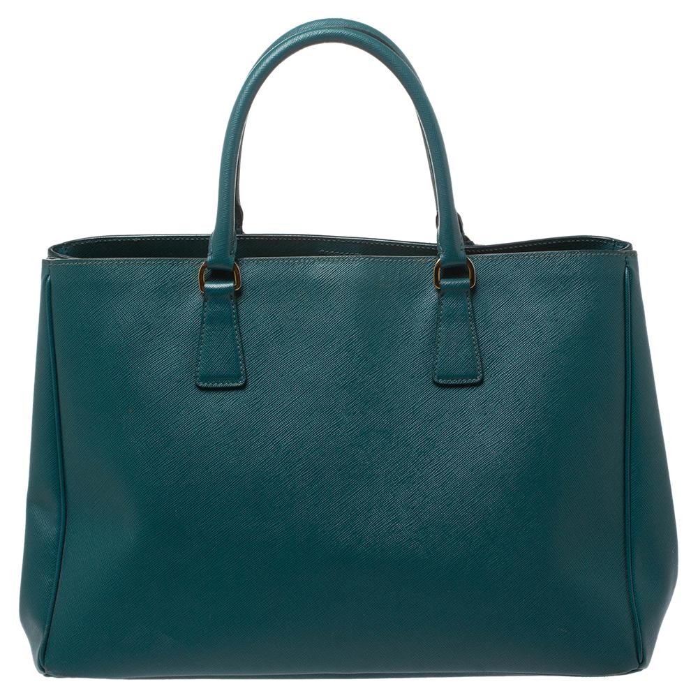 High in appeal and style, this tote is a Prada creation. It has been crafted from Saffiano Lux leather and shaped to exude class and luxury. The bag comes with two handles and a spacious nylon interior for your ease. Protective metal feet and the