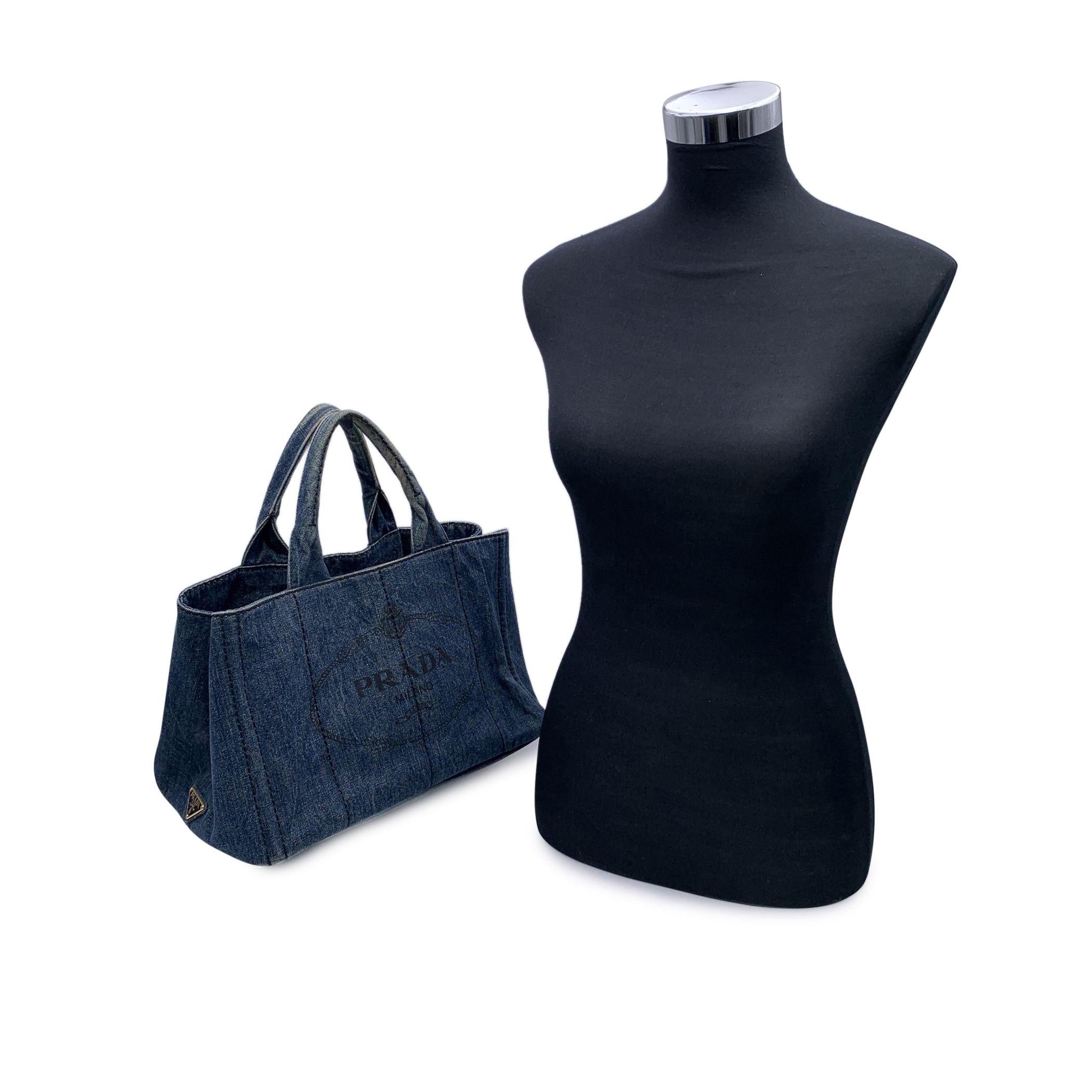 Prada Canapa tote bag in avio blue denim hemp canvas with printed Prada logo and Prada triangle logo on the sides. Mod. B1877G. Canvas handles. Removable and adjustable shoulder strap. Open top with side snap buttons. Canvas interior with 2 side zip