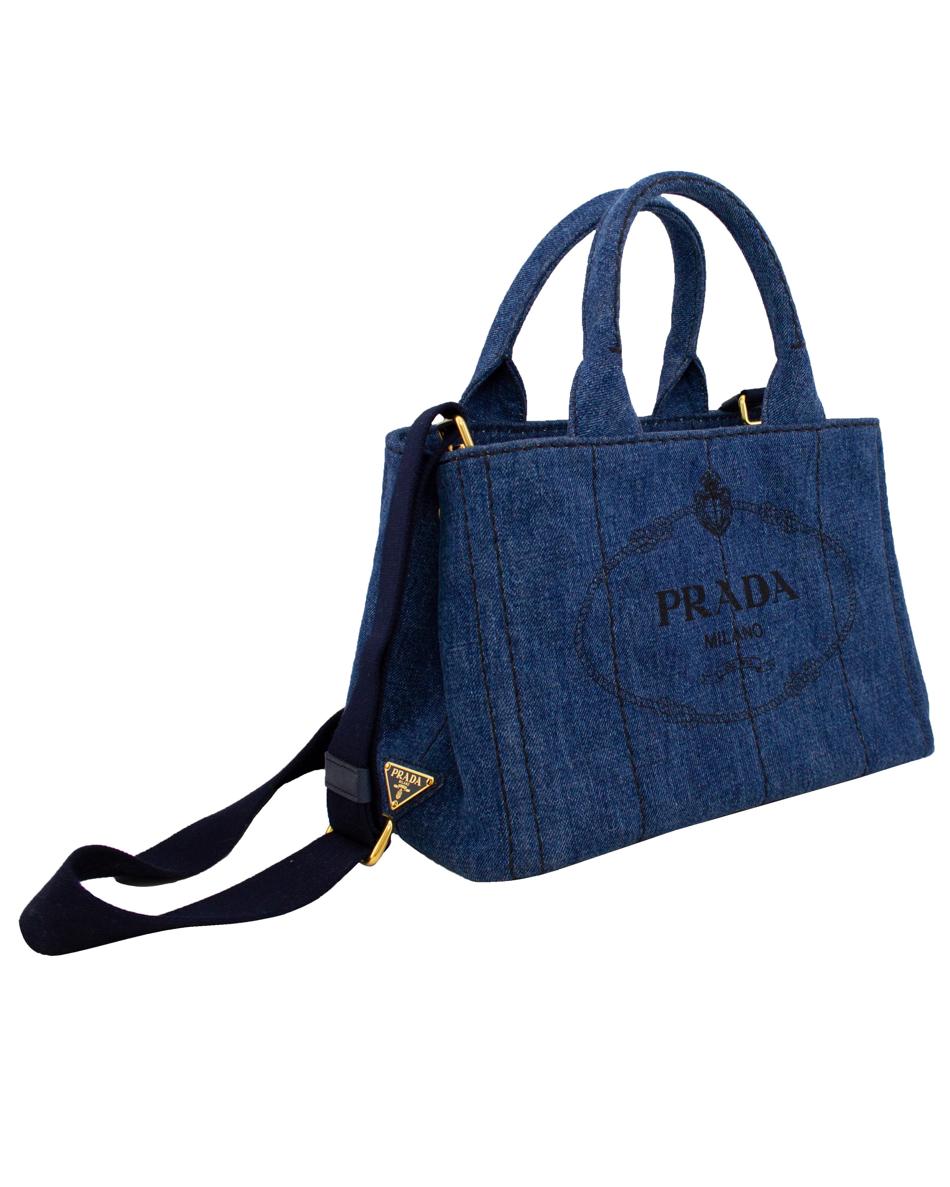  This current Prada tote bag was inspired by vintage gardener's bags. Denim printed with a silk-screen logo and embellished with brass-finish hardware, it offers three practical internal pockets and a detachable shoulder strap. Excellent vintage