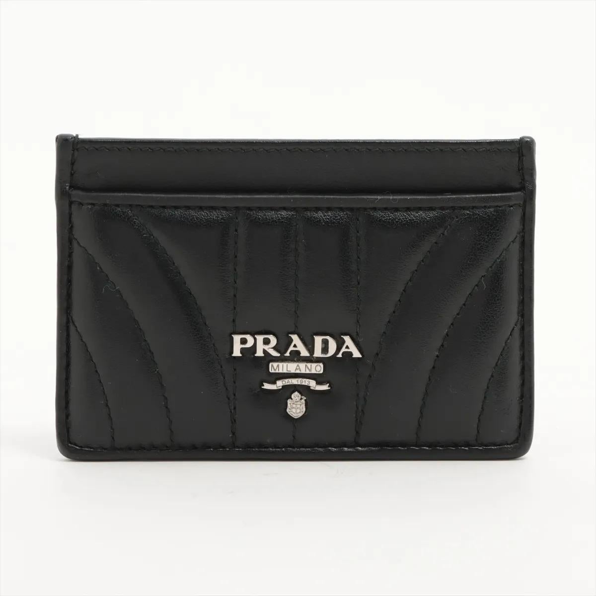 Il portacarte Prada Diagramme in pelle nera è una dimostrazione di moderna eleganza e raffinata maestria. Realizzata in lussuosa pelle trapuntata, presenta le caratteristiche cuciture Diagramme, che le conferiscono una texture distintiva e