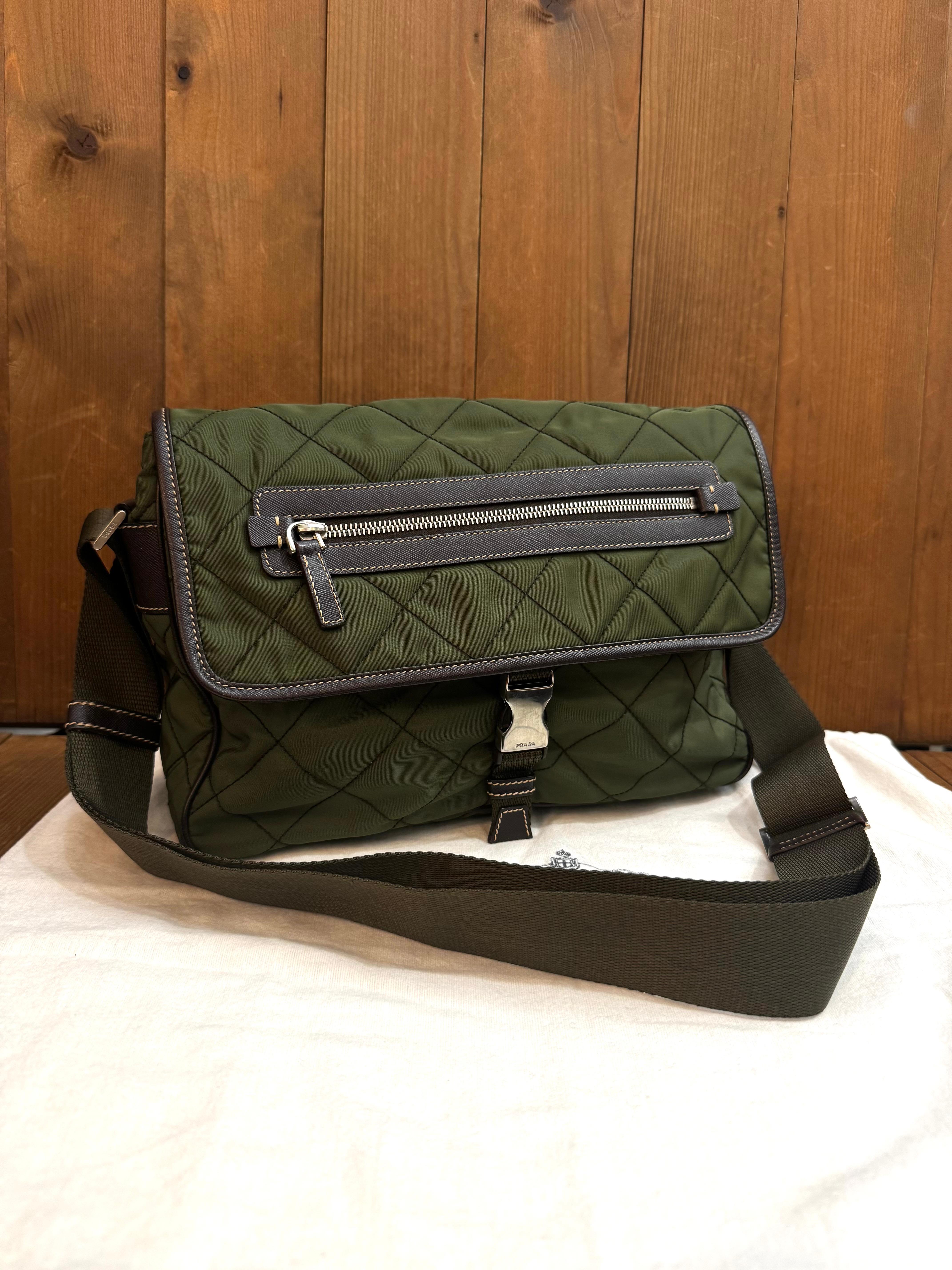 This stylish PRADA messenger crossbody bag is crafted of diamond quilted Tessuto polyester in army green featuring stainless steel hardware and Saffiano leather trims. Front flap buckle closure opens to an army green jacquard interior featuring a