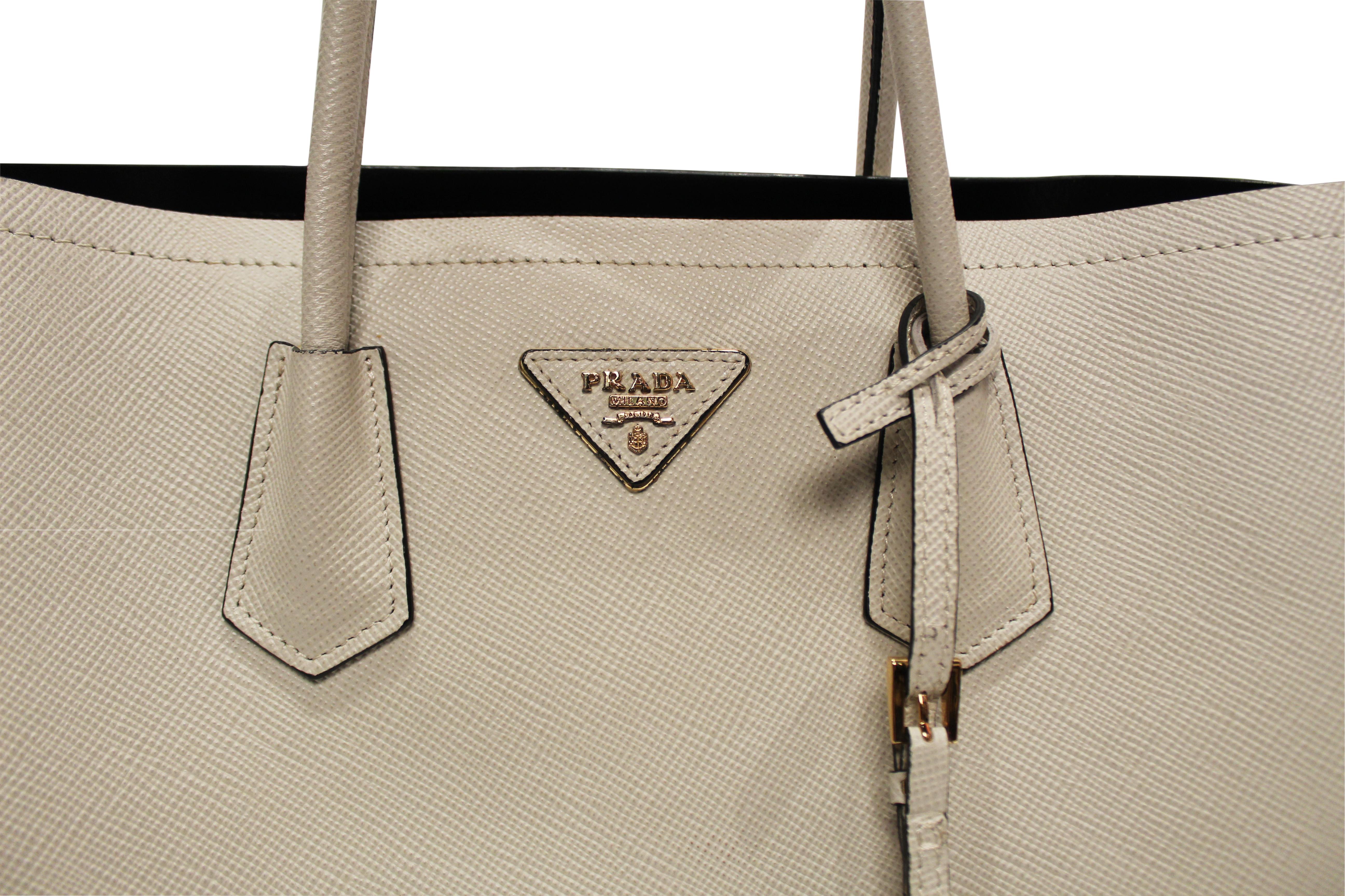 Light Beige Saffiano leather PRADA Double Bag in medium with gold toned hardware. This structured and spacious bag provides dual compartments, divided by interior flap pocket for valuables. This gorgeous bag has a soft nappa leather interior and
